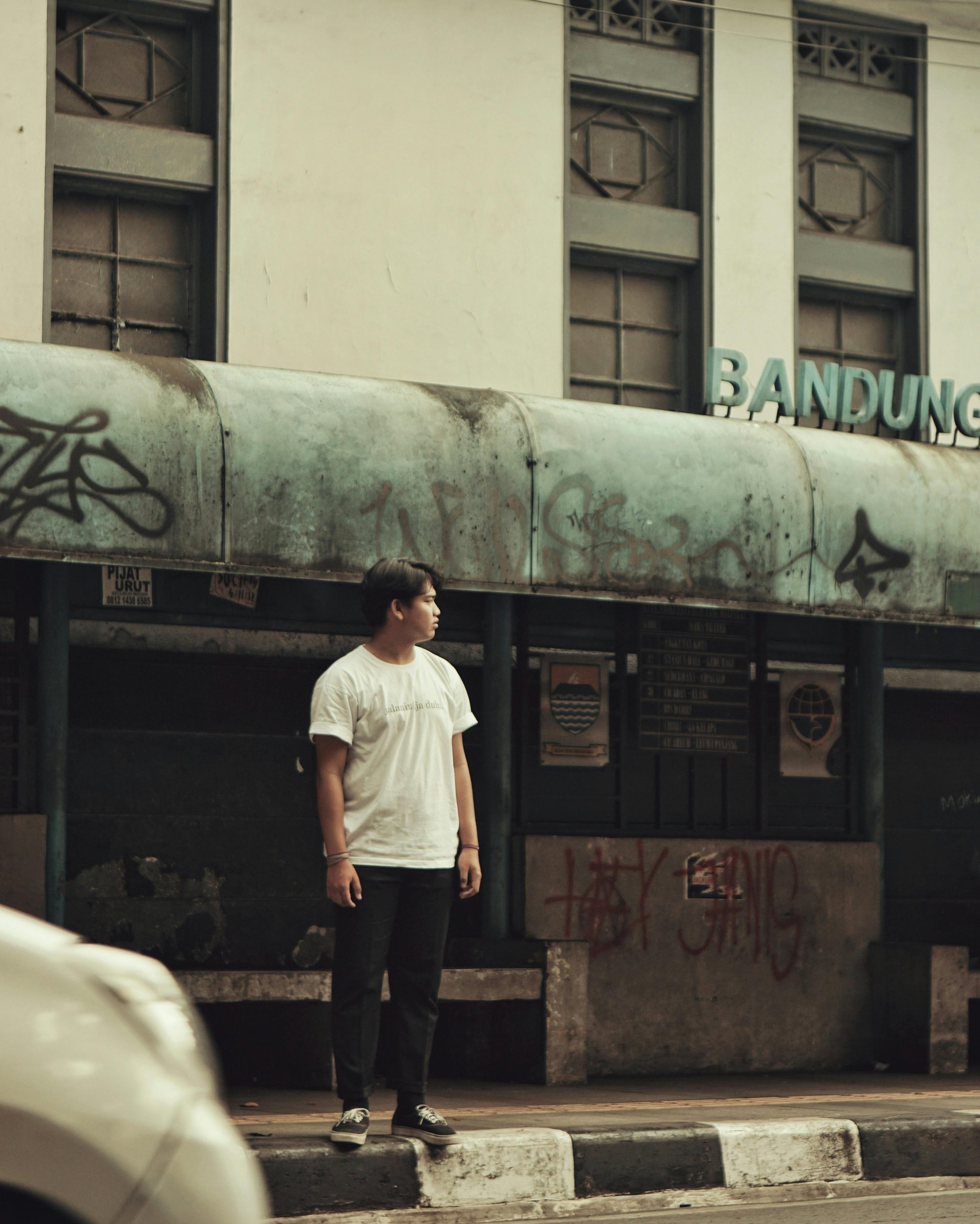 Young man in white t-shirt standing in urban street of Bandung, Indonesia.